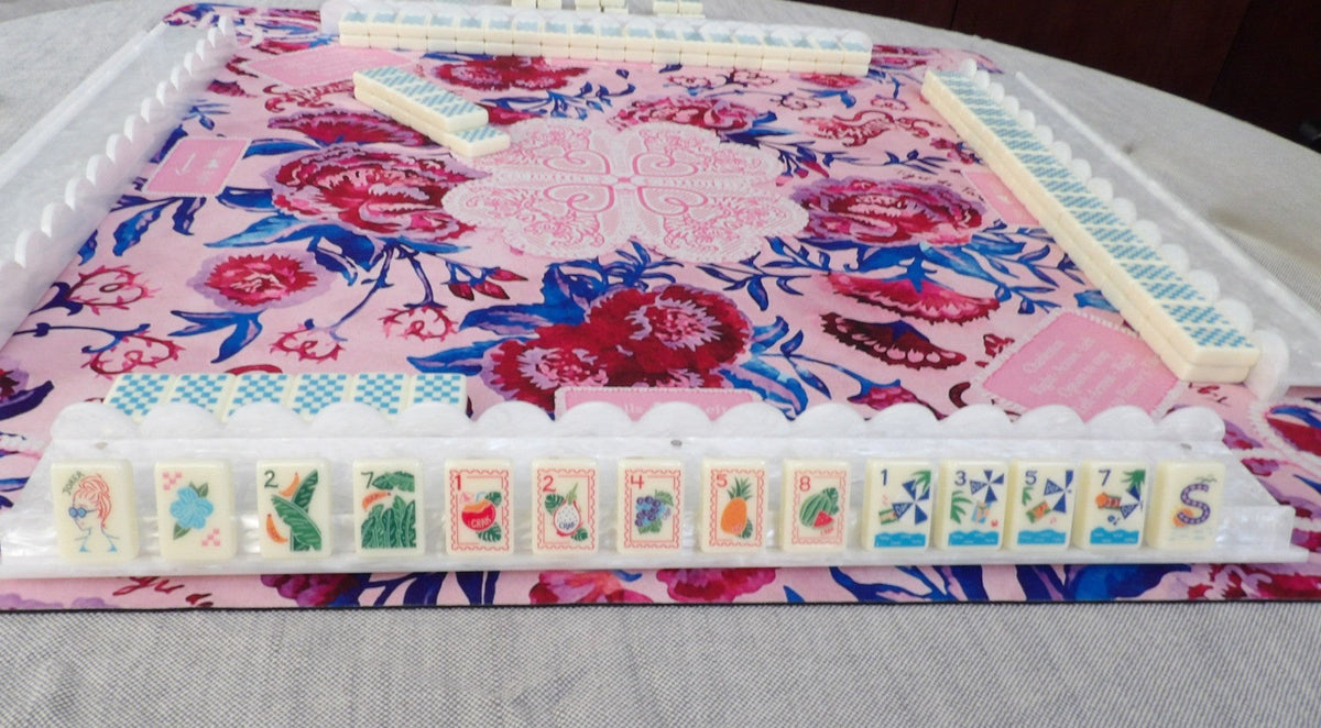 Luxury Mahjong tropical vacation themed set with colorful illustrated tiles on a pink floral game mat
