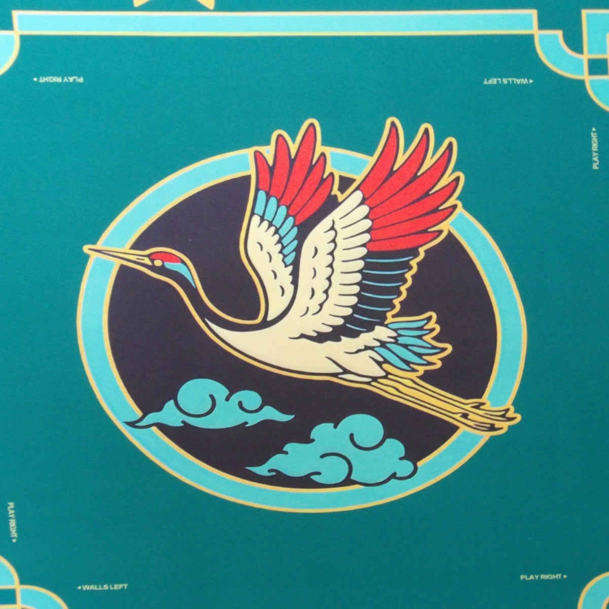 Close-up of the Jade Crane mahjong mat crane medallion in red, cream and turquoise on a midnight ground