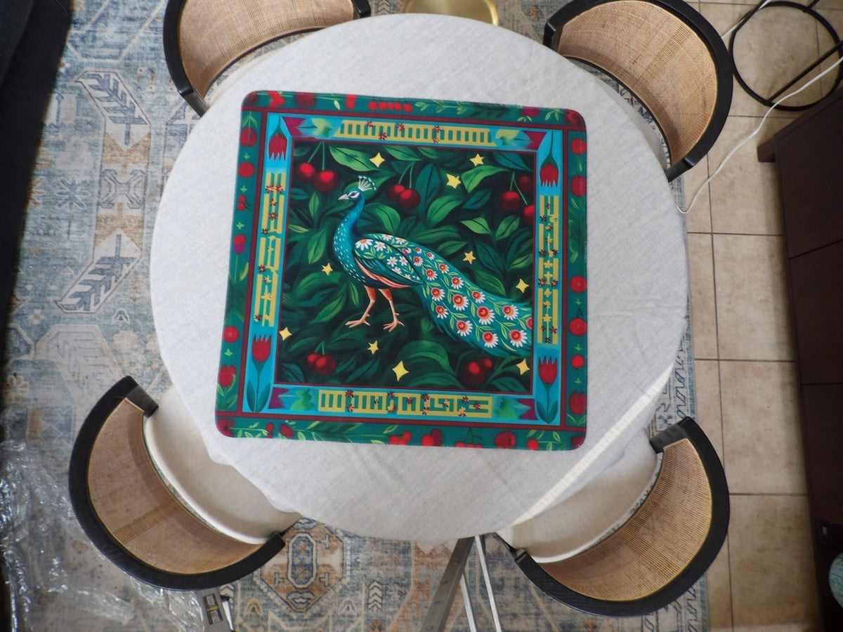 Teal peacock mahjong mat with a daisy-eyed tail on dark green foliage with red cherries and gold stars
