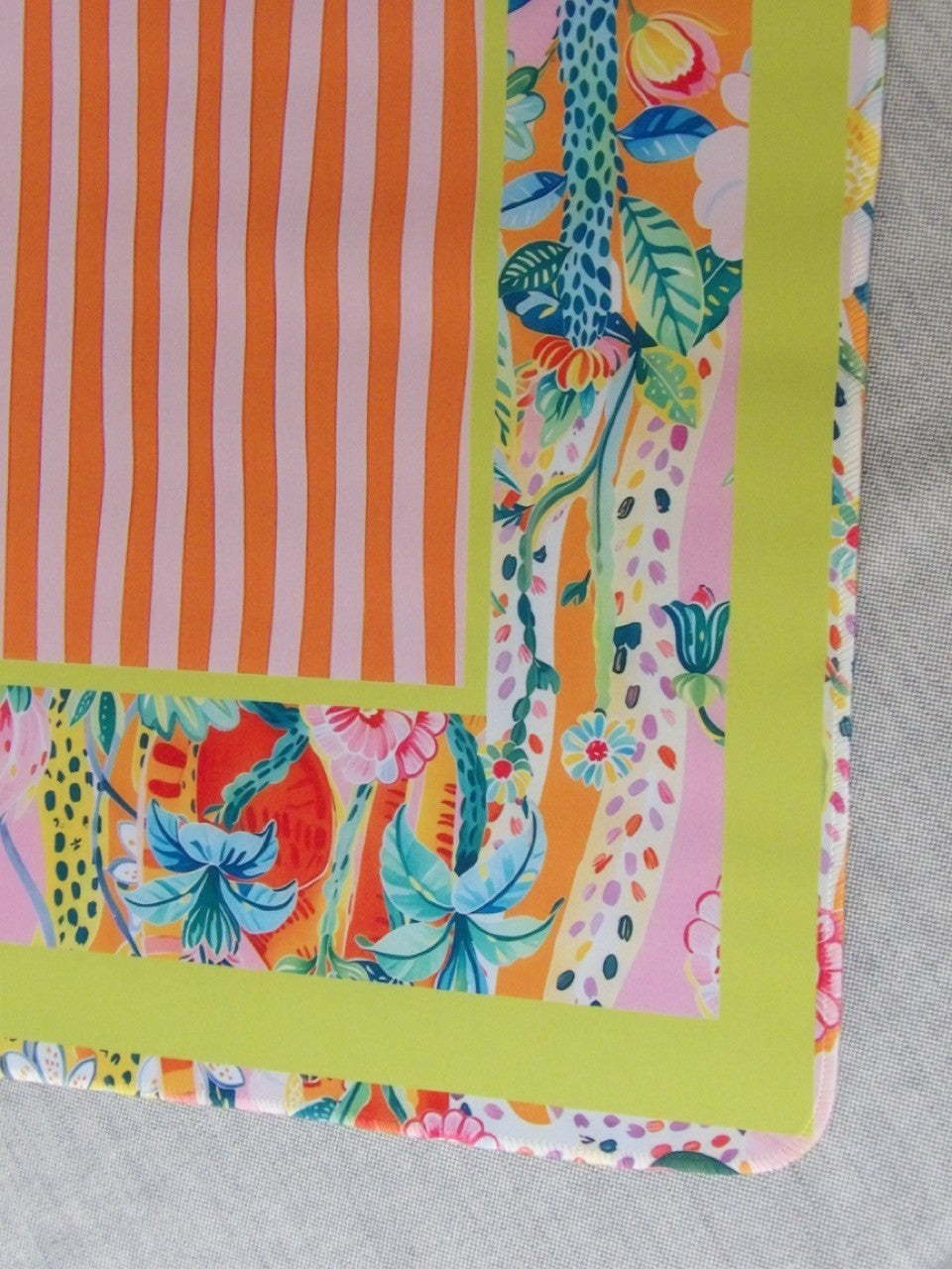 Corner detail of the Cabana Bloom mahjong mat where the chartreuse frame meets the tropical floral border