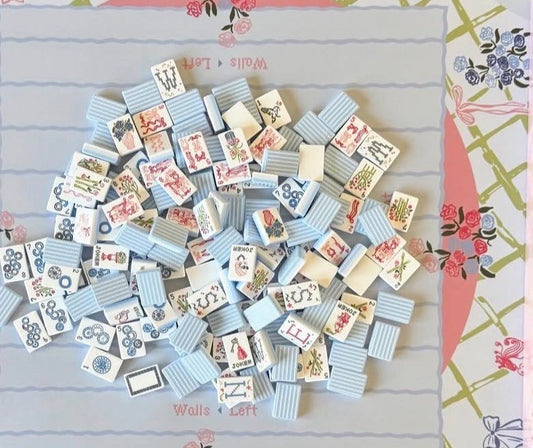 Luxury Mahjong grandmillennial set with blue ombré needlepoint-style tiles featuring floral and ribbon illustrations.