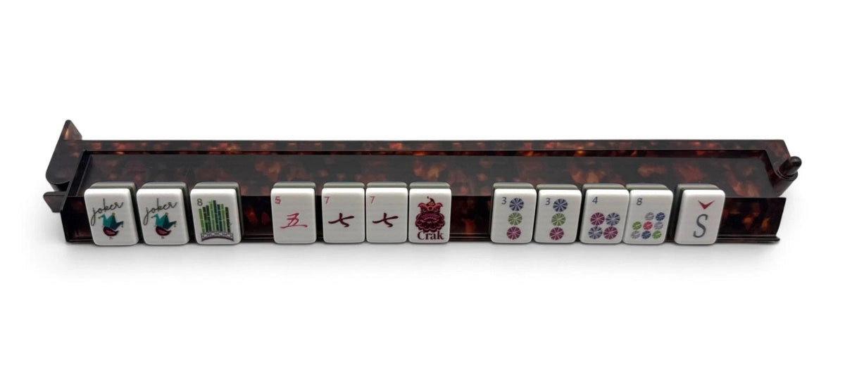 Luxury Mahjong tortoiseshell acrylic rack with hinged pusher holding a row of mahjong tiles on a white background