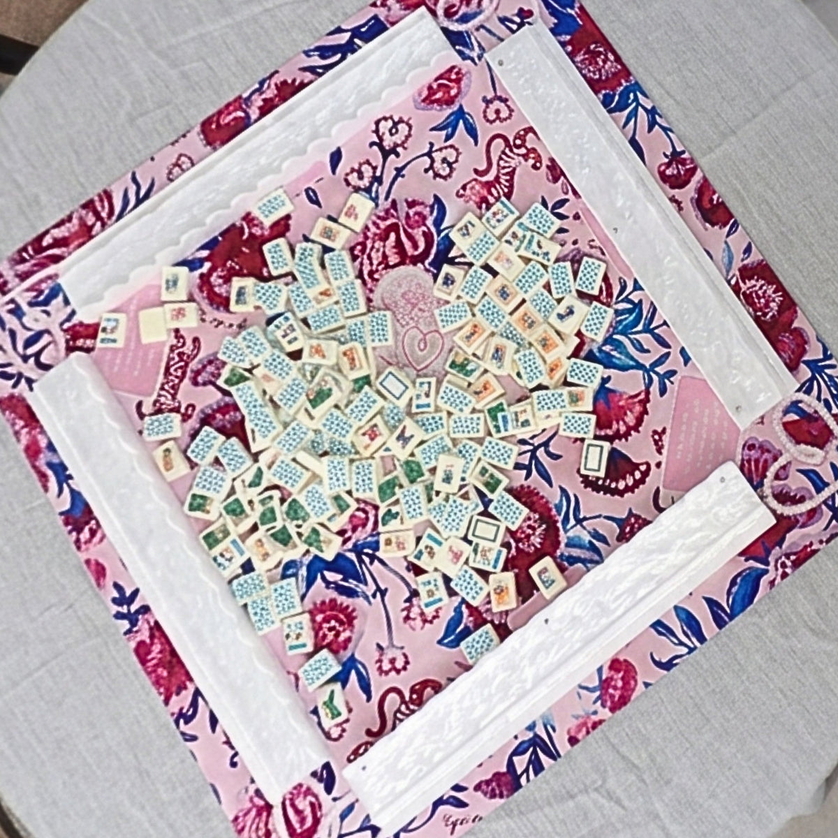 Luxury Mahjong tropical vacation themed tiles with colorful illustrations on a pink floral patterned game mat